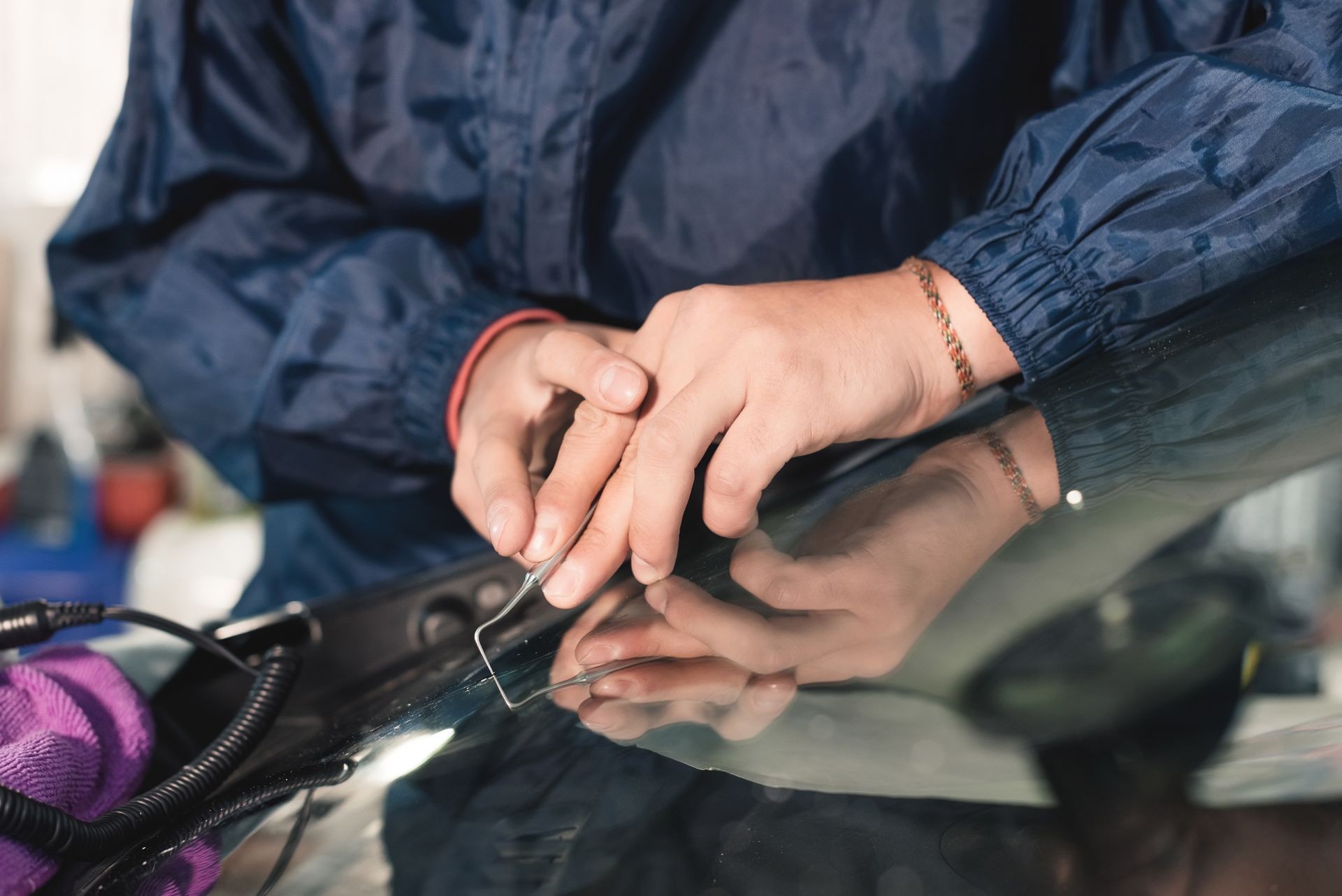 Close up Car glaze worker fixing and repairing a windshield or windshield of a car at a garage service station. Drill glass for repair